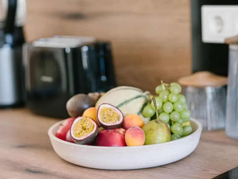 Kitchen with fruit basket and modern white cabinetry at Stay Eden MOONSTONE GREEN, a Ramstein TDY apartment.