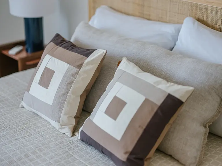 Master bedroom in the Stay Eden MOONSTONE GREEN apartment in Ramstein, featuring a neatly made bed with cozy decorative pillows.