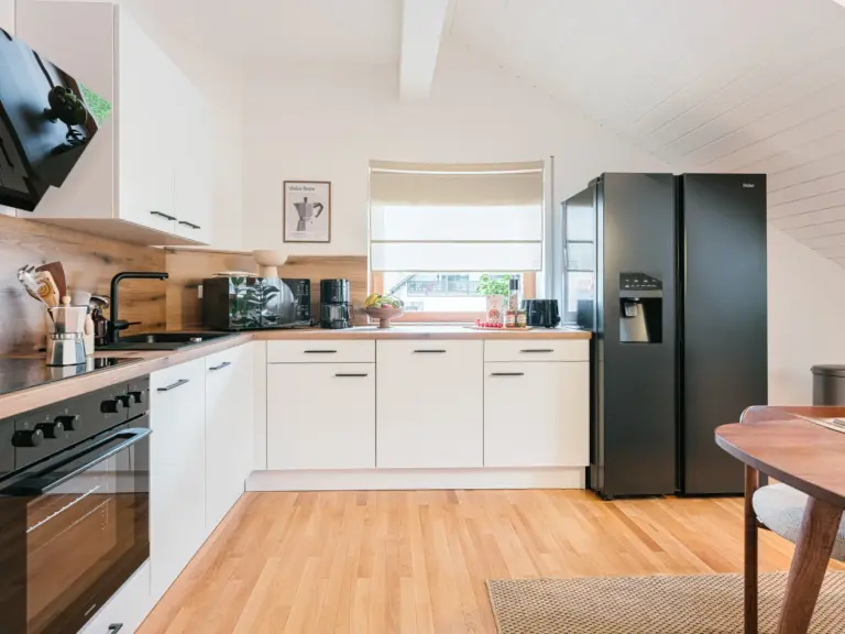 Modern kitchen with white cabinetry and wood accents at Stay Eden TOPAZ BLUE near Ramstein Air Base.