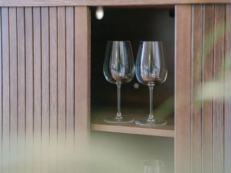 Living room sideboard with wine glasses and modern decor at Stay Eden TOPAZ BLUE near Ramstein Air Base.