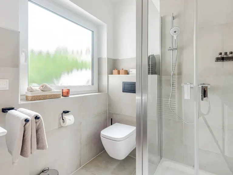 Bright main bathroom with walk-in shower and heated towel rack at Stay Eden TOPAZ GREEN near Ramstein Air Base.