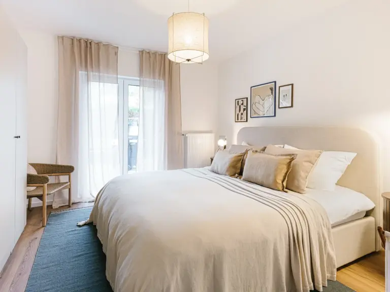 Bright master bedroom with king-size bed and natural light at Stay Eden TOPAZ GREEN near Ramstein Air Base.