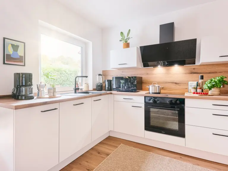 View of modern kitchen with white cabinetry and wood accents at Stay Eden TOPAZ GREEN near Ramstein Air Base.