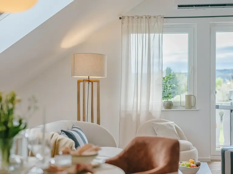 Bright living room in the Stay Eden SAPPHIRE BLUE apartment in Ramstein, featuring large windows with a pleasant exterior view.