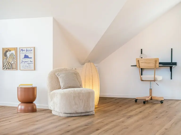 Dedicated workspace and lounge chair in the Stay Eden SAPPHIRE BLUE apartment in Ramstein, featuring a modern desk setup and a cozy seating area.