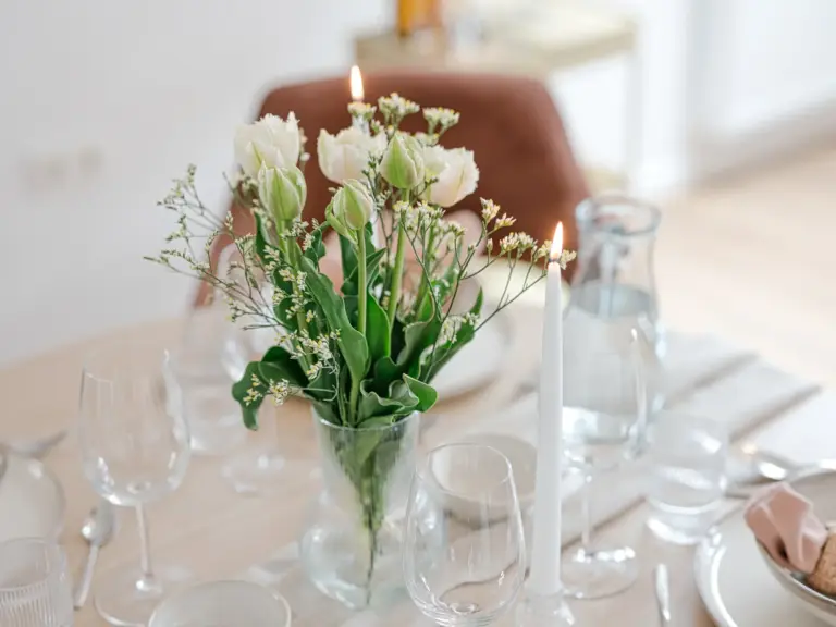 Dining area in the Stay Eden SAPPHIRE BLUE apartment in Ramstein, featuring a modern table decorated with fresh or decorative flowers.