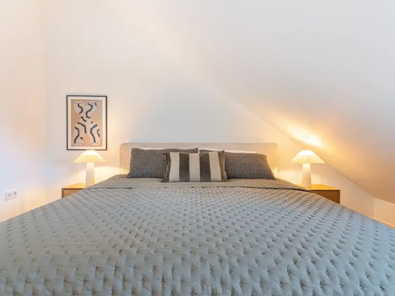 Master bedroom in the Stay Eden SAPPHIRE BLUE apartment in Ramstein, featuring a large king-size bed with modern bedding.