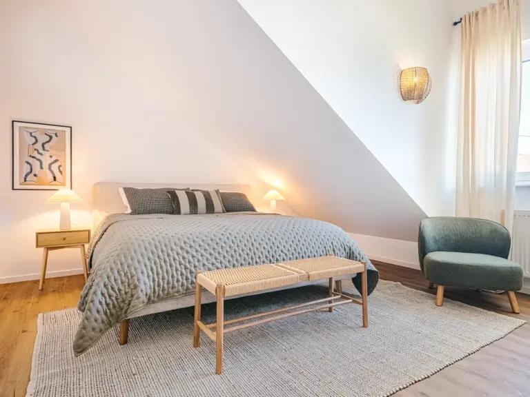 Master bedroom in the Stay Eden SAPPHIRE BLUE apartment in Ramstein, featuring a spacious king-size bed with modern bedding and soft lighting.