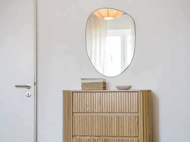 Master bedroom in the Stay Eden SAPPHIRE BLUE apartment in Ramstein, featuring a modern sideboard and a wall-mounted mirror.