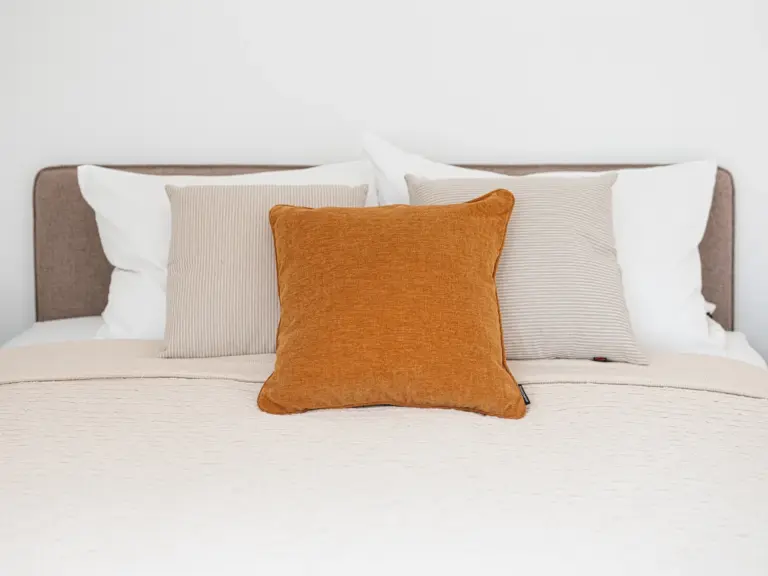 Second bedroom in the Stay Eden SAPPHIRE BLUE apartment in Ramstein, featuring a neatly made bed with cozy decorative pillows.